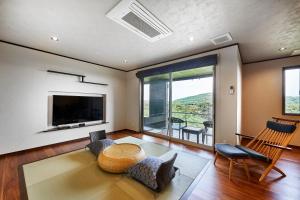 a living room with a television and a table and chairs at Kisara Bettei TOKI in Toba