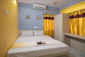 a bedroom with a white bed with a yellow curtain at Collection O Yellow Rose in kolkata