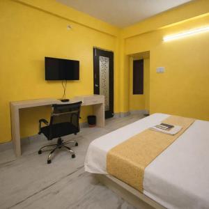 a bedroom with a desk and a bed and a computer at Collection O Yellow Rose in kolkata