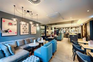 a restaurant with blue couches and tables and chairs at Premier Inn Koeln City Centre in Cologne