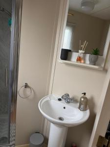 a bathroom with a white sink and a mirror at my happy place caravan in Trusthorpe