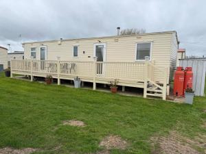 a mobile home with a deck and a yard at my happy place caravan in Trusthorpe