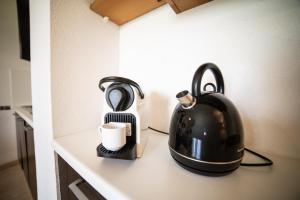 a black tea kettle and a cup on a counter at Le Bellevue, 50m lac, piscine, parking, wifi, baignade surveillée in Aureilhan