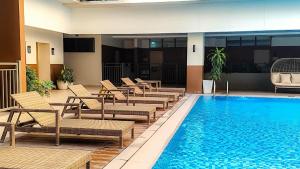 a pool with chaise lounge chairs next to a hotel at Be Residences Studio in Cebu City