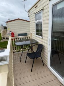a patio with a table and chairs on a balcony at my happy place caravan in Trusthorpe