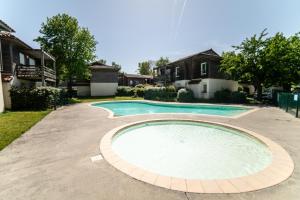 a swimming pool in a yard with houses at Le Bellevue, 50m lac, piscine, parking, wifi, baignade surveillée in Aureilhan