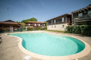 a large swimming pool in a yard with buildings at Le Bellevue, 50m lac, piscine, parking, wifi, baignade surveillée in Aureilhan
