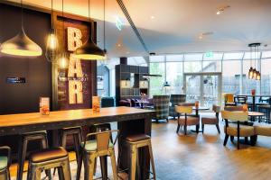 a restaurant with a bar and tables and chairs at Premier Inn Stuttgart Bad Cannstatt in Stuttgart