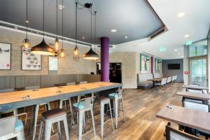 a restaurant with a bar with stools and tables at Premier Inn Stuttgart Bad Cannstatt in Stuttgart