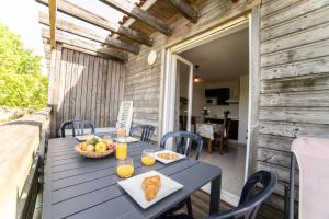 a table with a bowl of fruit and a basket of orange juice at Le Bellevue, 50m lac, piscine, parking, wifi, baignade surveillée in Aureilhan