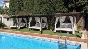 two beds in a gazebo next to a pool at Casa EntreAzules l Vivienda Rural in Lecrin