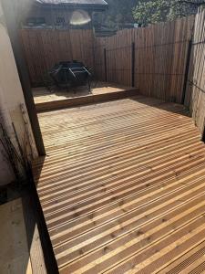 a wooden deck with a grill in a backyard at Idéal we, vacances travail in Sainte-Hélène-sur-Isère