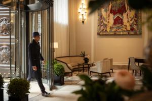 a man in a suit and hat walks through a lobby at Corinthia Rome in Rome +113 photos