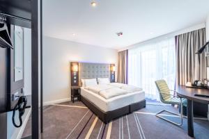 a hotel room with a bed and a desk at Premier Inn München City Schwabing in Munich +17 photos