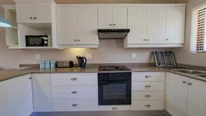 a kitchen with white cabinets and a stove top oven at Sue Casa 3 in Margate +17 photos