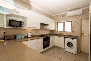 a kitchen with white cabinets and a washer and dryer at Sue Casa 3 in Margate