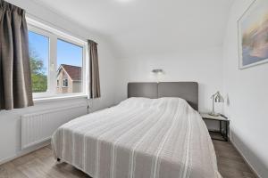 a white bedroom with a large bed and a window at Mosselbank 073 - Noordzeepark Ouddorp in Ouddorp