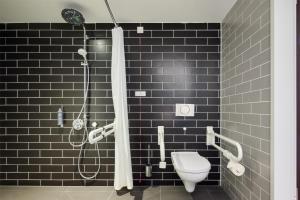 a bathroom with a toilet and a shower with black tiles at Premier Inn Stuttgart City Centre in Stuttgart