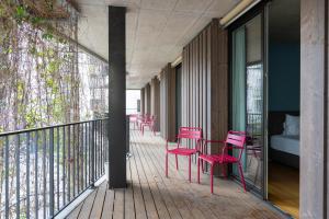 a balcony with red chairs and a bed on it at Gästehaus Hunziker in Zurich