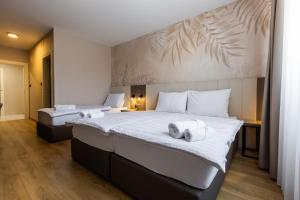 two beds in a hotel room with towels on them at Hotel Klek in Ogulin