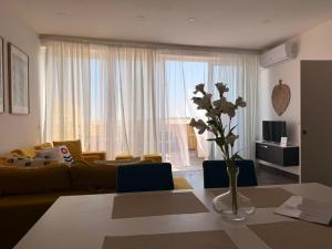 a living room with a yellow couch and a vase with flowers at De Rock Penthouse in Sannat