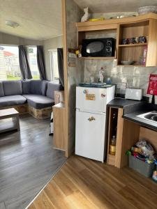 a small kitchen with a white refrigerator in a caravan at 6Berth Caravan-Wheelchair Accessible-Pet Friendly in Skegness +8 photos