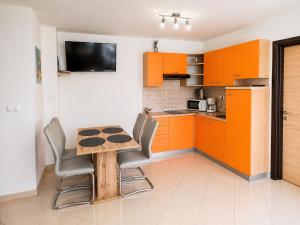 a kitchen with orange cabinets and a wooden table and chairs at Apartments Mia in Baška