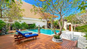 a backyard with a pool and a bench and trees at D'Avera Villa Canggu in Canggu