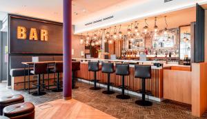 a bar with bar stools in a restaurant at Premier Inn München Airport Süd in Hallbergmoos