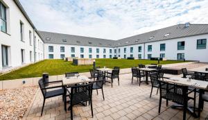 an outdoor patio with tables and chairs in a building at Premier Inn München Airport Süd in Hallbergmoos