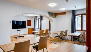 a room with tables and chairs and a flat screen tv at Premier Inn München Airport Süd in Hallbergmoos