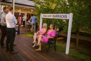two women sitting on a bench next to a sign at The Historic Railway Barracks in Goulburn