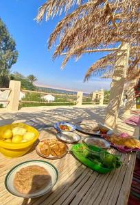 a table with plates of food on a table under an umbrella at Tunis Tone Ecolodge & Campsite in Fayoum
