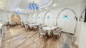 a dining room with tables and chairs and a chandelier at Saroy Khiva in Khiva