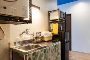 a kitchen with a sink and a black refrigerator at Guest House BLUE DOOR in Imabari Railway Station
