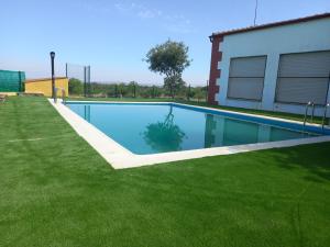 a swimming pool with green grass next to a building at Alojamiento Turístico Río Uces in La Zarza de Pumareda