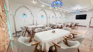 a dining room with tables and chairs and a flat screen tv at Saroy Khiva in Khiva