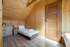 a small bedroom with a bed and a wooden wall at Widokowa osada drewnianych domków, tuż przy szlakach turystycznych in Brenna
