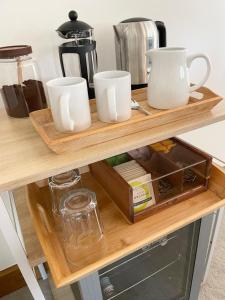 a shelf with three cups and a coffee maker on it at The Silver Suite at Manor Farm in Edenbridge