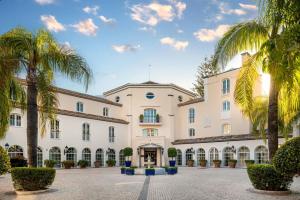 an exterior view of a large building with palm trees at Grand Hotel Las Dunas, Autograph Collection in Estepona