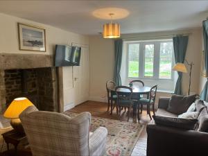 a living room with a fireplace and a table and chairs at Castle Lodge Haughton Castle in Hexham