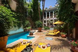 a swimming pool with lounge chairs and a building at El Fenn in Marrakesh