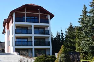 a white apartment building with a gambrel roof at Ruciane Residence in Ruciane-Nida