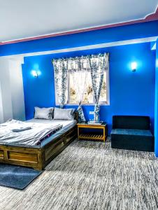 a blue bedroom with a bed and a couch at Mayal Lyang Lachung in Mangan