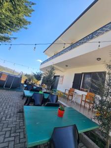 a patio with green tables and chairs and a building at Baza Hostel - Swimming Pool in Berat