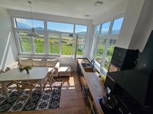 a living room with a table and chairs and windows at Baza Hostel - Swimming Pool in Berat