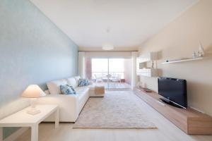 sala de estar con sofá blanco y TV en Rocha Blue Sea Apartment, en Portimão