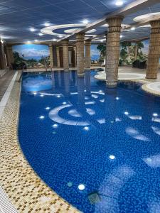 a large pool with blue water in a building at Hayot Hotel Skazka in Qarshi