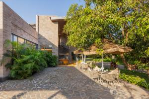 an exterior view of a house with chairs and umbrellas at The Forest Chapter by Sayaji Sasan Gir in Chitrod
