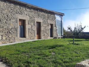 a stone building with a grassy yard in front of it at Alojamiento Turístico Río Uces in La Zarza de Pumareda